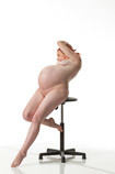 Nude pregnant female art model in a seated pose