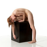 Nude female art model leaning over a box