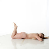 Artist reference photos of a nude curvy full figured female figure model posed laying on the floor