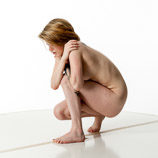 Artist reference photos of a slim nude blond female art model in a squatting pose